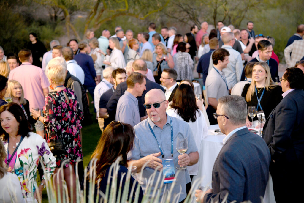 Group of event attendees networking during a cocktail reception outside.